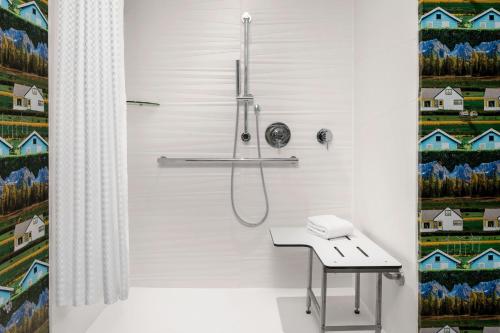 La salle de bains est pourvue d'une douche avec rideau de douche. dans l'établissement Aloft Houston Shenandoah - The Woodlands, à Shenandoah