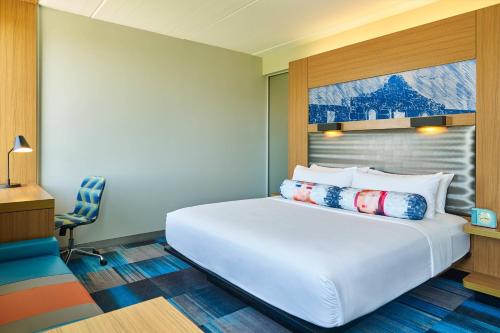 a bedroom with a large white bed and a chair at Aloft San Antonio Airport in San Antonio