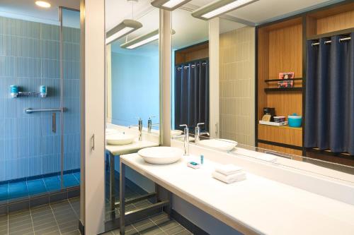 a bathroom with two sinks and two mirrors at Aloft San Antonio Airport in San Antonio