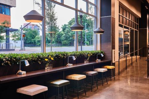 a row of stools in a restaurant with windows at The Casso, Raleigh, a Tribute Portfolio Hotel in Raleigh