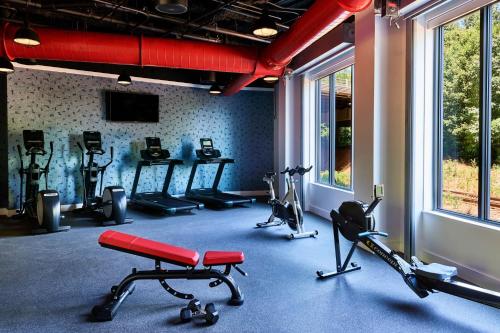 a gym with several exercise bikes in a room with windows at The Casso, Raleigh, a Tribute Portfolio Hotel in Raleigh