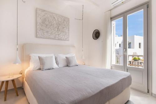 a white bedroom with a bed and a window at Brand New Cozy Studio with Balcony at the center of Naousa in Naousa