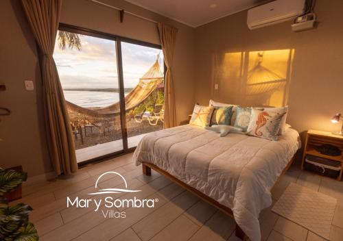 a bedroom with a bed with a view of the ocean at Mar y Sombra Villas in Quepos