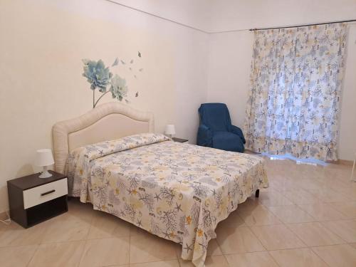 een slaapkamer met een bed en een blauwe stoel bij Casa Ortigia in Siracusa