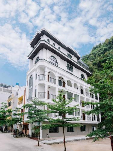 a white building with a tree in front of it at Cat Ba Green Pearl Hotel in Cat Ba