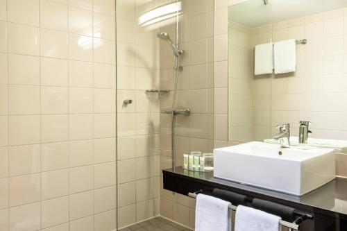 La salle de bains est pourvue d'un lavabo et d'une douche. dans l'établissement Courtyard by Marriott Paris Saint Denis, à Saint-Denis