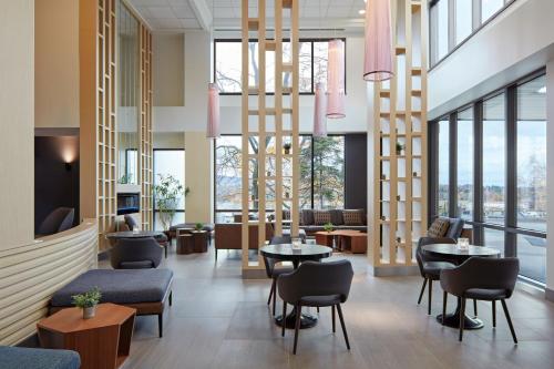 a lobby with tables and chairs and windows at Delta Hotels by Marriott Sherbrooke Conference Centre in Sherbrooke