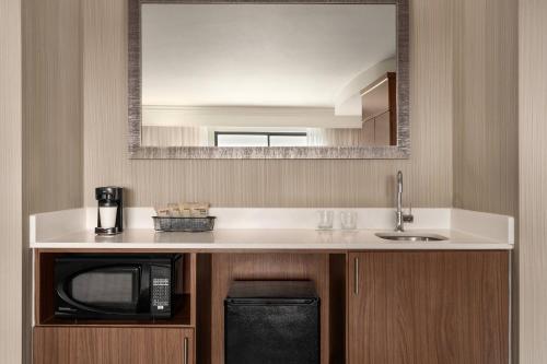 a kitchen with a microwave and a sink and a mirror at Courtyard by Marriott Philadelphia Montgomeryville in North Wales