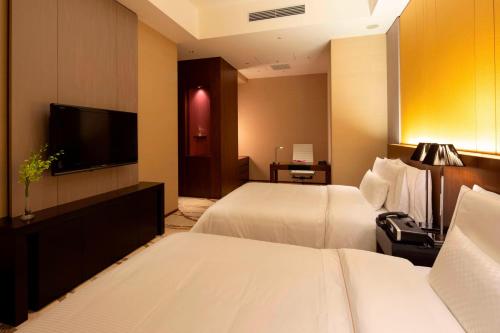 a hotel room with two beds and a flat screen tv at The Westin Sendai in Sendai