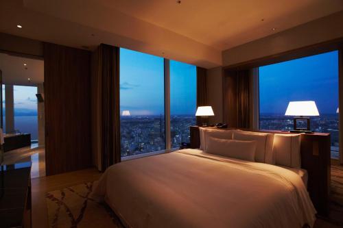 a bedroom with a large bed with large windows at The Westin Sendai in Sendai