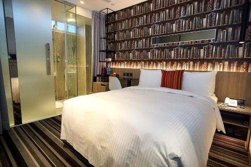 a bedroom with a white bed and a wall of books at Via Hotel - Zhongxiao in Taipei