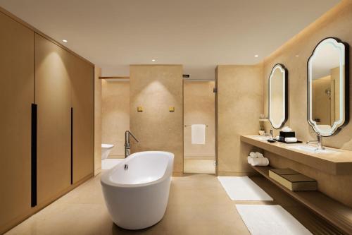 a bathroom with a large white tub and two sinks at Indore Marriott Hotel in Indore