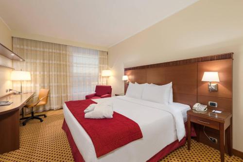 a hotel room with a large bed and a desk at Courtyard by Marriott Venice Airport in Tessera