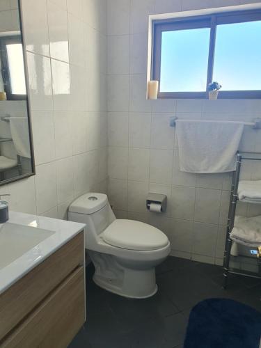 a bathroom with a toilet and a sink and a window at Peñuelas Club in Coquimbo