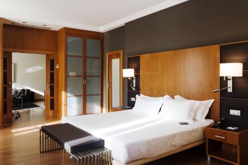 a bedroom with a large white bed with a wooden headboard at AC Hotel Almería by Marriott in Almería