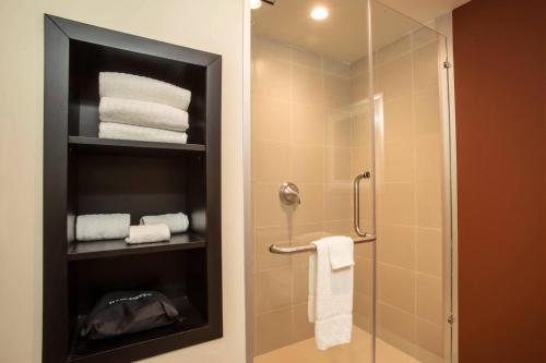 a bathroom with a glass shower stall with towels at Courtyard Toluca Tollocan in Toluca