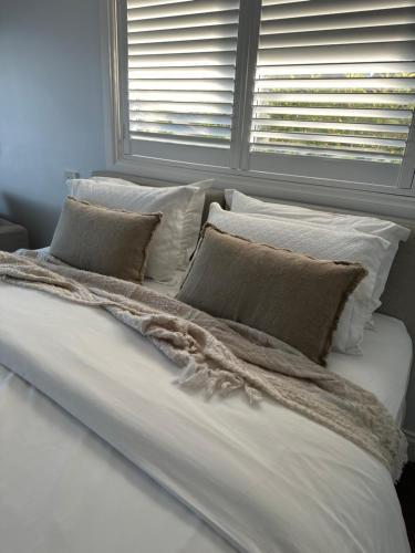 1 cama blanca grande con almohadas y ventana en B & B On The Water en Sanctuary Point