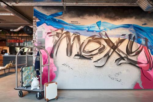 a wall with graffiti on it with a luggage cart at Moxy Amsterdam Schiphol Airport in Hoofddorp