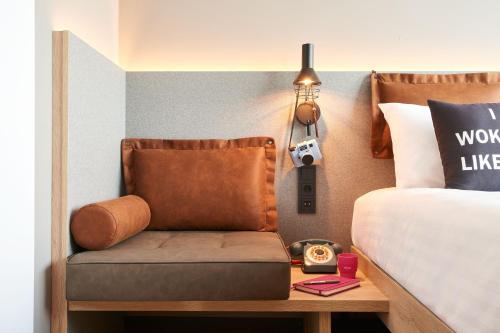 a bed room with a chair next to a bed at Moxy Amsterdam Schiphol Airport in Hoofddorp