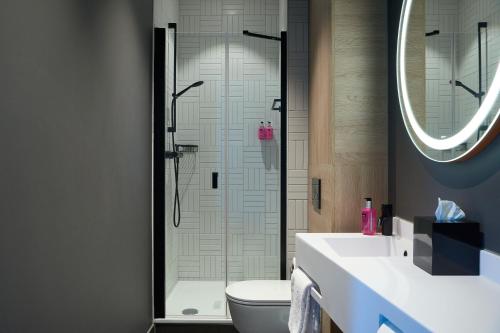 a bathroom with a shower and a toilet and a sink at Moxy Amsterdam Schiphol Airport in Hoofddorp