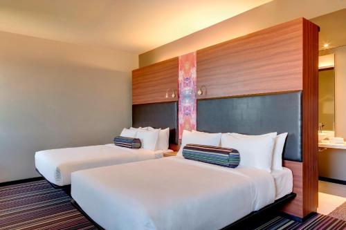 two beds in a hotel room with white pillows at Aloft Asuncion in Asunción