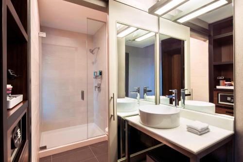 La salle de bains est pourvue de 2 lavabos et d'une douche. dans l'établissement Aloft Boston Seaport District, à Boston