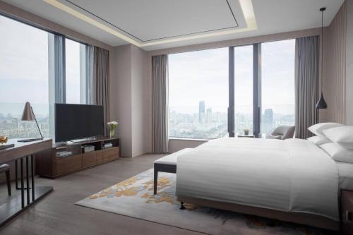 a bedroom with a large white bed and a television at Courtyard by Marriott Suzhou Mudu in Suzhou