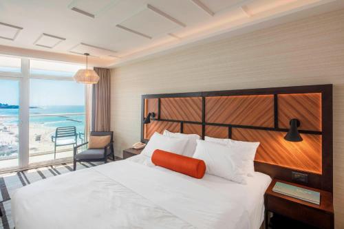 sypialnia z białym łóżkiem i pomarańczową poduszką w obiekcie Renaissance Tel Aviv Hotel w Tel Awiwie