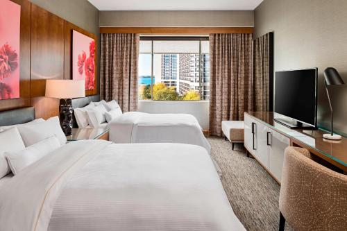 a hotel room with two beds and a flat screen tv at The Westin Harbour Castle, Toronto in Toronto
