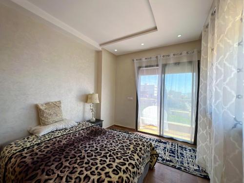 1 dormitorio con cama y ventana grande en Appartement Amwaj, en Plage de Mehdia