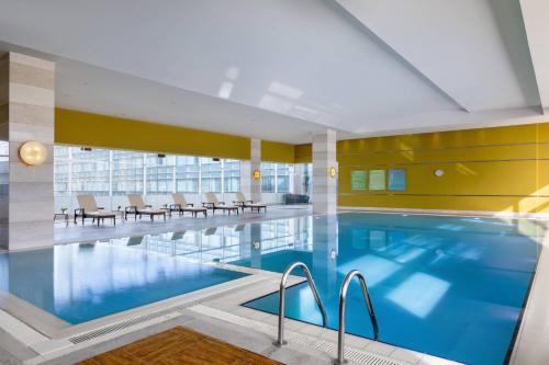 a large swimming pool in a building with chairs and tables at Renaissance Atyrau Hotel in Atyraū