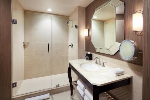 y baño con lavabo y ducha con espejo. en Sheraton McKinney, en McKinney