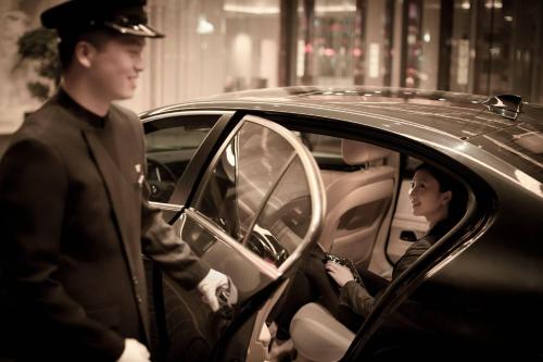 a man standing next to a woman sitting in a car at JW Marriott Hotel Beijing Central in Beijing