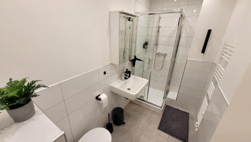 y baño blanco con lavabo y ducha. en Business & Family - Zentral, 24h Check-In, XXL TV, en Siegburg