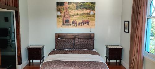 a bedroom with a bed with two night stands and a painting at Delightful on Devonport in Tauranga
