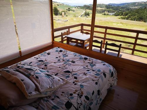 Łóżko w pokoju z balkonem z widokiem na okolicę w obiekcie Cabaña con vista a la laguna de Tota w mieście Tota