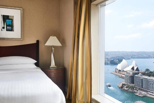 a bedroom with a window with a view of the sydney opera house at Sydney Harbour Marriott Hotel at Circular Quay in Sydney