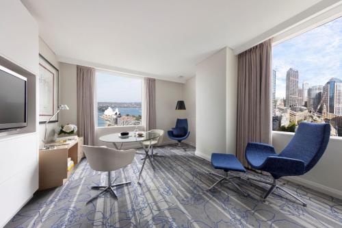 a hotel room with a table and chairs and a large window at Sydney Harbour Marriott Hotel at Circular Quay in Sydney