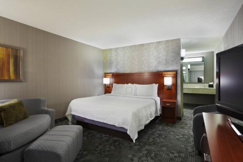 a hotel room with a bed and a couch at Courtyard Chicago St. Charles in Saint Charles