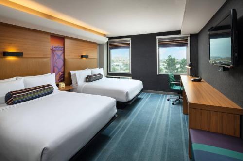 a hotel room with two beds and a desk at Aloft San Francisco Airport in Millbrae