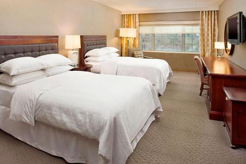 a hotel room with two beds and a desk at Sheraton Rockville in Rockville