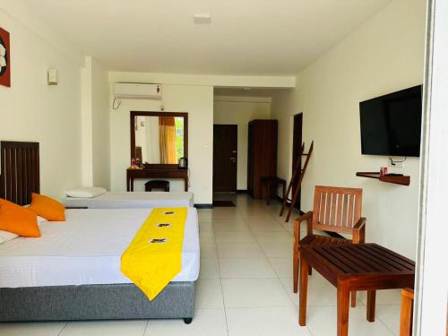 1 dormitorio con 2 camas, TV y silla en Kandy Hub Guest House, en Kandy