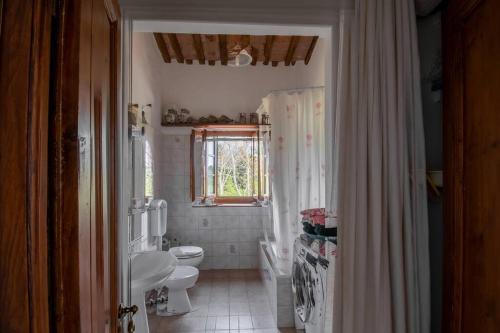 een badkamer met een wastafel, een toilet en een raam bij Appartamento con vista panoramica in Chianti in San Donnino