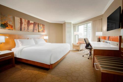1 dormitorio con 1 cama blanca grande y escritorio en Delta Hotels by Marriott London Armouries en Londres