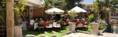 a group of people sitting at a table in a garden at Hotel Andenes in Arequipa