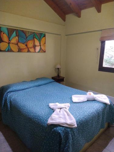 Un dormitorio con una cama azul con toallas. en CABAÑAS VILLA CAMPESTRE en Potrerillos