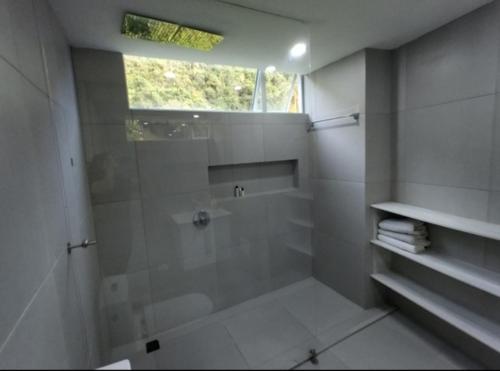 a white bathroom with a shower and a window at Mirador samsara in La Calera