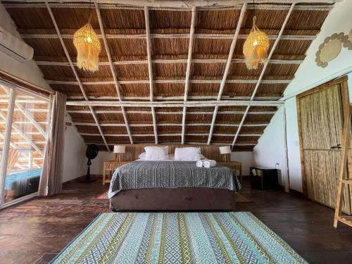 a bedroom with a bed and a wooden ceiling at NENA BEACH CLUB & HOTEL in Baru