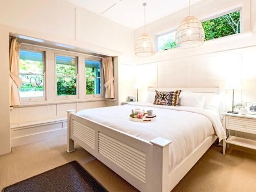 a white bedroom with a large bed with a tray of fruit on it at Leura Country Cottage in Leura