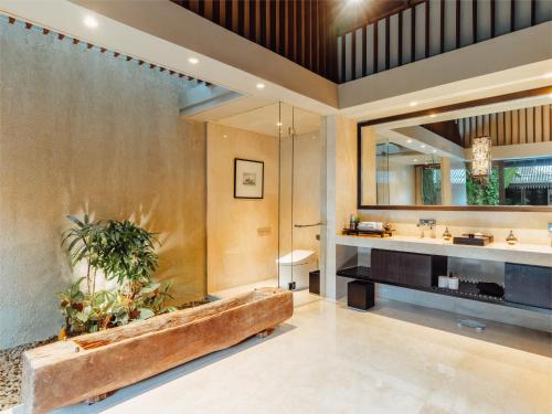 La salle de bains est pourvue d'une grande baignoire et d'un grand miroir. dans l'établissement Ametis Villa -Adult Only, à Canggu